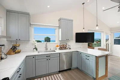 a kitchen with white cabinets and a sink and a tv at New with Panoramic View in Sunset Cliffs in San Diego