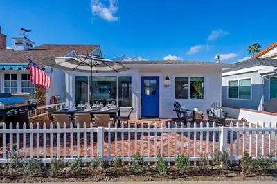 a house with a white fence and a table with an umbrella at Balboa Beach Getaway Steps2Sand Firepit BBQ in Newport Beach