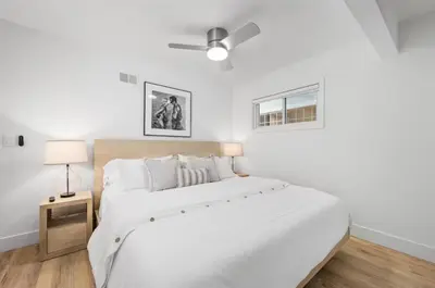 a white bedroom with a large bed and a lamp at Balboa Beach Getaway Steps2Sand Firepit BBQ in Newport Beach