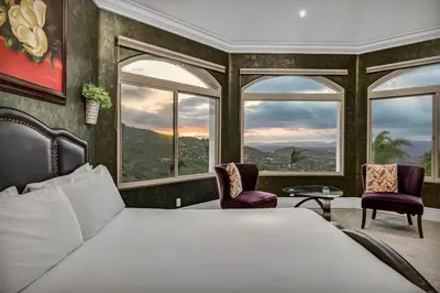 a bedroom with a bed and two chairs and windows at Secluded Boulder Groves Resort Getaway! in Ramona