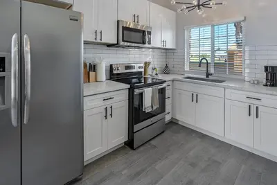 a kitchen with white cabinets and a black refrigerator at San Diego Large Luxury home near Downtown in San Diego
