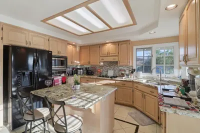 a kitchen with wooden cabinets and a black refrigerator at Entire Private Home with 5 Bedrooms 4 Bathrooms, 3-Acres Estate, 3000 sqft, near Winery in Fallbrook, Available Now in Fallbrook