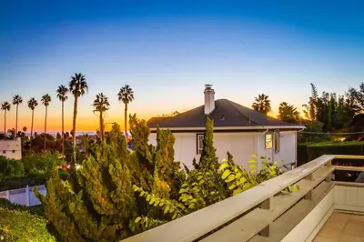 a house with a fence and some trees and palm trees at Beryl Bungalow in San Diego