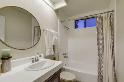 a white bathroom with a sink and a mirror at Beryl Bungalow in San Diego