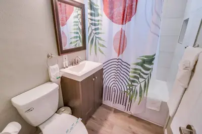 a bathroom with a sink and a toilet and a shower curtain at Casa Azul Lower in San Diego