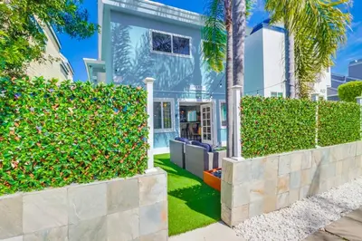 a house with a hedge and palm trees at Casa Azul Lower in San Diego