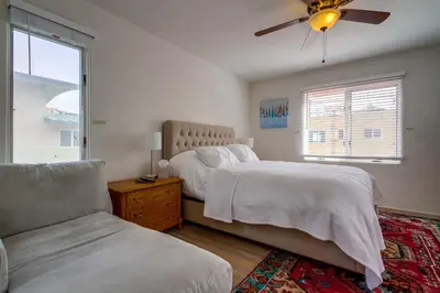 a bedroom with two beds and a couch and a window at Casa Rosa in San Diego