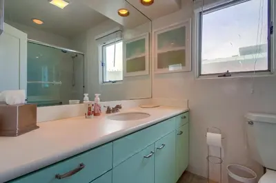 a bathroom with a sink and a mirror and a toilet at Casa Rosa in San Diego