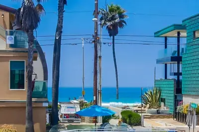 a beach with palm trees and a blue umbrella at Manhattan Shores 1B in San Diego