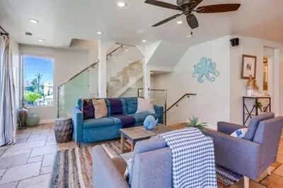 a living room with blue couches and a ceiling fan at Ocean Breeze 1 in San Diego