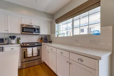 a kitchen with white cabinets and a microwave and a window at Seaglass Shores in San Diego