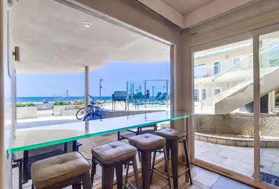 a dining room with a glass table and stools at Surf Rider D in San Diego