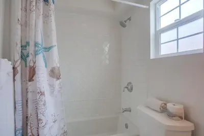 a white bathroom with a shower curtain and a toilet at Pacific Pearl in San Diego