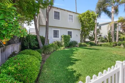 a white fence in front of a house with a yard at 500 ft to Ocean Relaxing stay Parking WiFi 838 in San Diego
