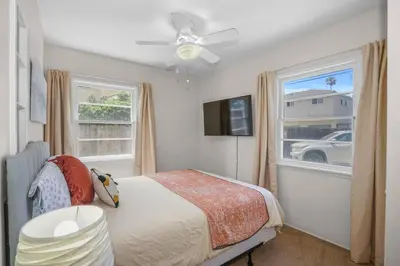 a bedroom with a bed with a ceiling fan and a window at 500 ft to Ocean Relaxing stay Parking WiFi 840 in San Diego