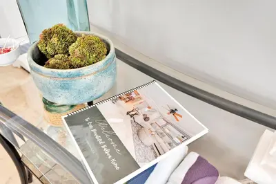 a glass table with a plant in a vase and a magazine at Beach Escape with Patio! 2 Min Walk to Sand & Surf in Newport Beach