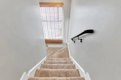 a staircase with a black hand rail and a window at Beach Escape with Patio! 2 Min Walk to Sand & Surf in Newport Beach