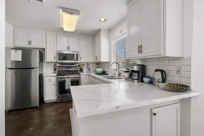 a kitchen with white cabinets and stainless steel appliances at Townhouse 1 Block From Bay With Yard & Parking in San Diego