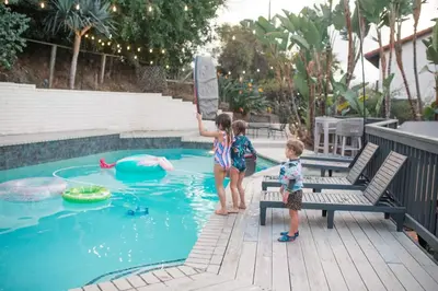two children standing next to a swimming pool at 5BR Oasis with Pool, Arcade, Sauna in La Mesa