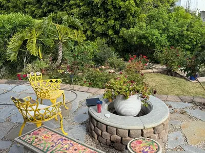 a patio with two chairs and a fire pit with flowers at Guesthouse in Coastal Del Mar, California in San Diego