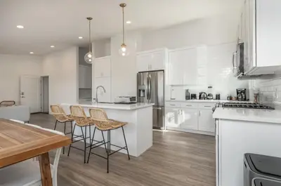 a kitchen with white cabinets and bar stools at Outsite San Diego - Encinitas Avocado in Encinitas