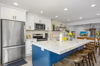 a kitchen with white cabinets and a large island with bar stools at Live in the Sunshine-DMBC148N in Solana Beach