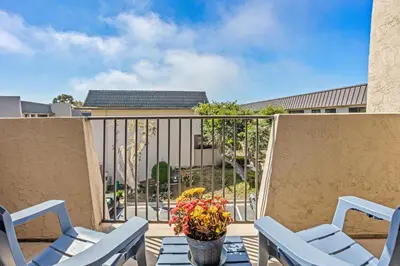 a balcony with chairs and a table with a vase of flowers at Live in the Sunshine-DMBC148N in Solana Beach