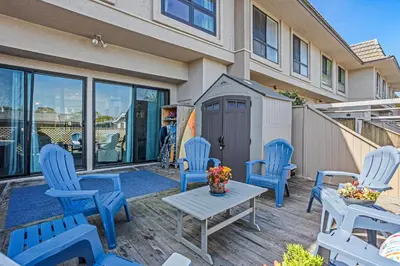 a patio with blue chairs and a table and a building at Live in the Sunshine-DMBC148N in Solana Beach