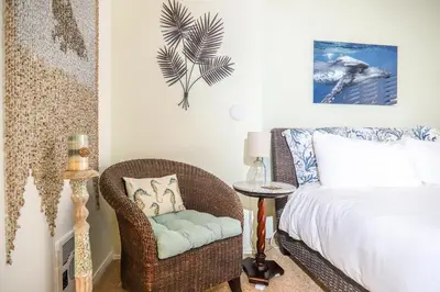a bedroom with a bed and a wicker chair at Sea La Vie - DMST17 in Solana Beach