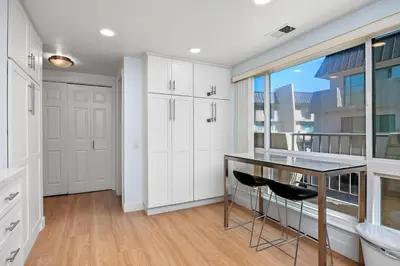 a kitchen with white cabinets and a table and chairs at Seaside Shenanigans - DMBC751P in Solana Beach