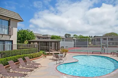 a swimming pool with chairs and a tennis court at Blissful SEA'renity - DMBC850S in Solana Beach