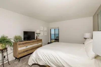 a bedroom with a bed and a flat screen tv at Oceanfront Sea'batical - SBTC212 in Solana Beach