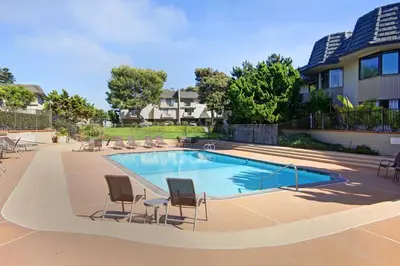 a swimming pool with chairs and a house at Second Wind - DMBC756S in Solana Beach