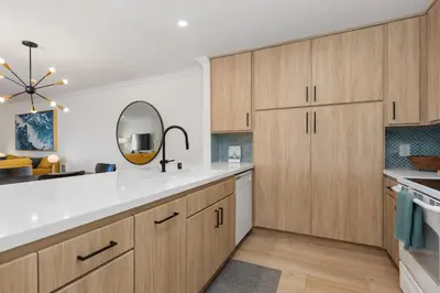 a kitchen with wooden cabinets and a sink and a mirror at Happy Days - SBTC101 in Solana Beach