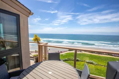 a balcony with a table and chairs and the ocean at Above the Waves - SUR116 in Solana Beach