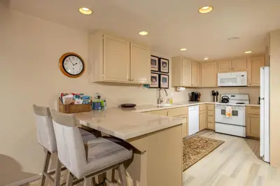 a kitchen with a counter and a clock on the wall at Above the Waves - SUR116 in Solana Beach