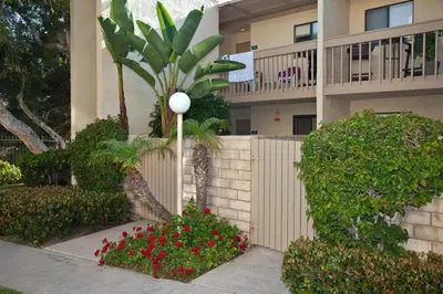 a building with a fence and flowers in front of it at Serenity By The Sea - SBTC202 in Solana Beach
