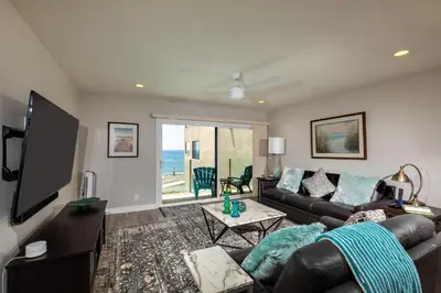 a living room with a couch and a flat screen tv at Serenity By The Sea - SBTC202 in Solana Beach