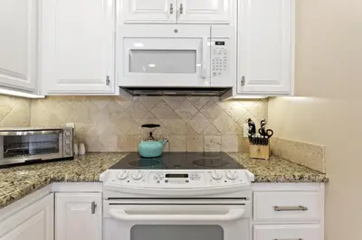 a kitchen with white cabinets and a stove and microwave at Bella Vista - SUR111 in Solana Beach