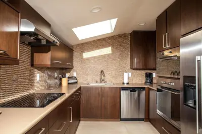 a kitchen with wooden cabinets and stainless steel appliances at Paradise Awaits - SUR182 in Solana Beach