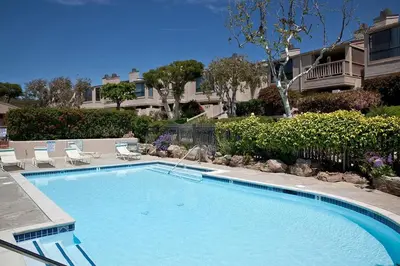 a large swimming pool with chairs and a house at Paradise Awaits - SUR182 in Solana Beach
