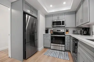 a kitchen with white cabinets and a stainless steel refrigerator at Tranquil Living - SUR4 in Solana Beach