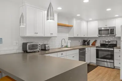 a kitchen with white cabinets and stainless steel appliances at Sun, Sand, & Vitamin Sea - SUR5 in Solana Beach