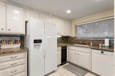 a kitchen with white cabinets and a white refrigerator at Relax & Renew - SONG8 in Solana Beach