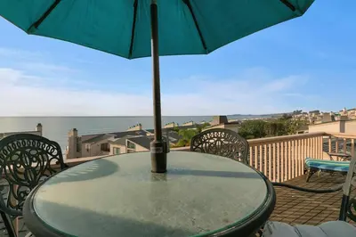 a table with an umbrella on top of a balcony at A Wave From It All - SUR42 in Solana Beach