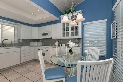 a kitchen with a glass table and white cabinets at A Wave From It All - SUR42 in Solana Beach