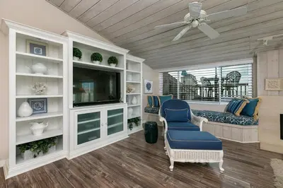 a living room with a tv and a blue chair at A Wave From It All - SUR42 in Solana Beach
