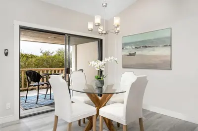 a dining room with a glass table and white chairs at Endless Summer - SUR149 in Solana Beach