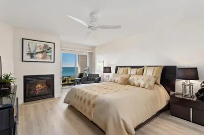a bedroom with a large bed and a fireplace at Don't Worry Beach Happy SONG13 in Solana Beach
