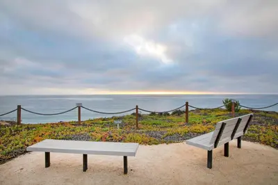 a bench sitting on the sand near the ocean at Don't Worry Beach Happy SONG13 in Solana Beach